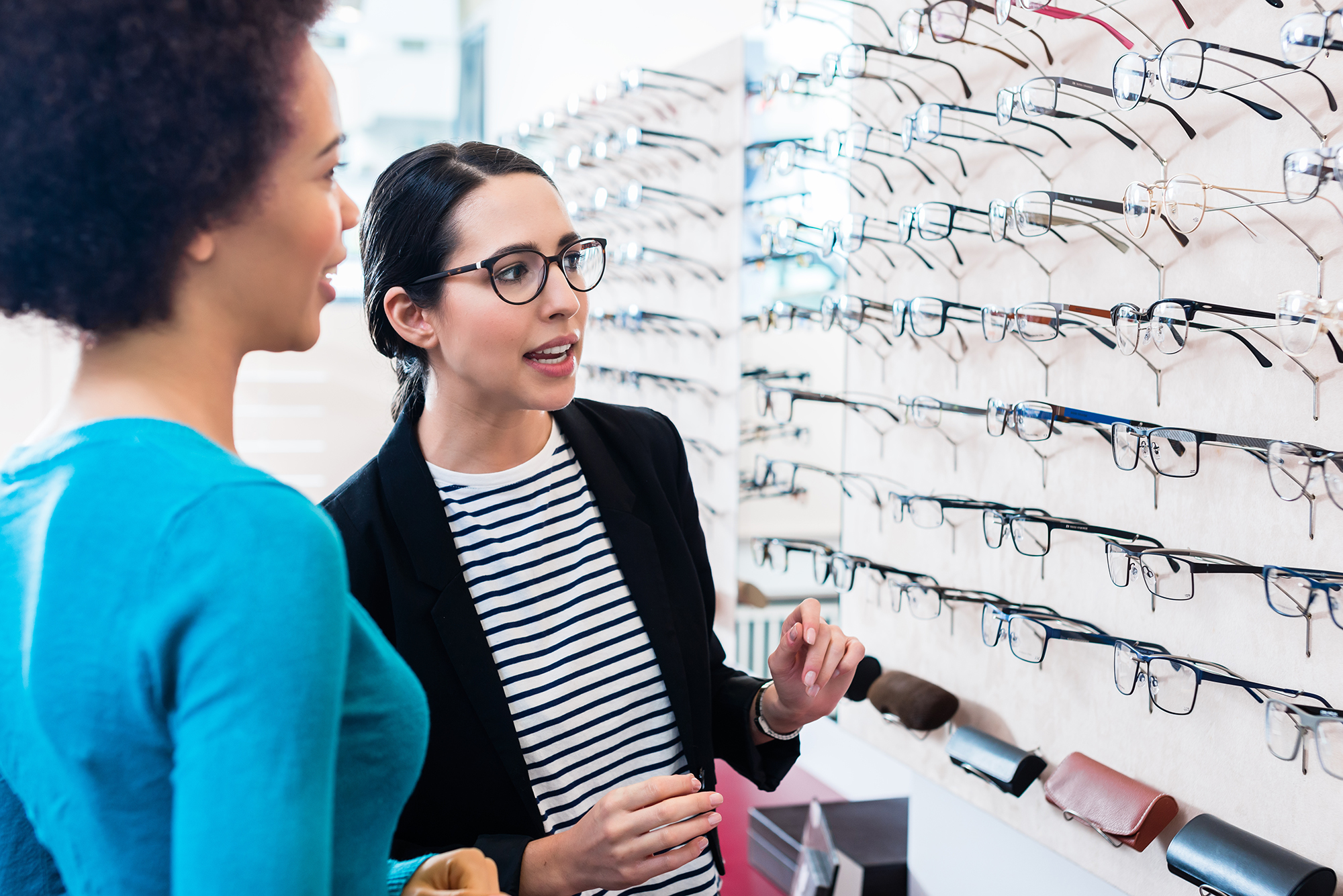 Black woman inspecting glasses in optician shelf